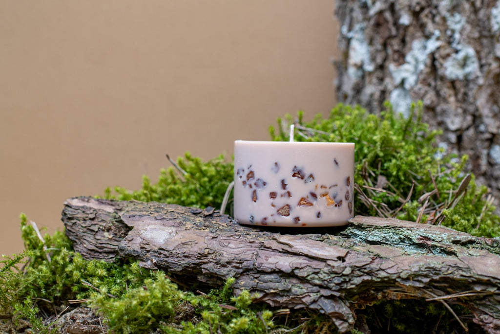 Bougie tilleul et miel en cire de soja ornée de fleurs séchées, posée sur un rondin moussu