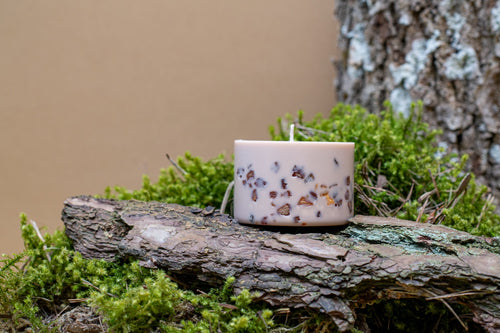 Bougie tilleul et miel en cire de soja ornée de fleurs séchées, posée sur un rondin moussu