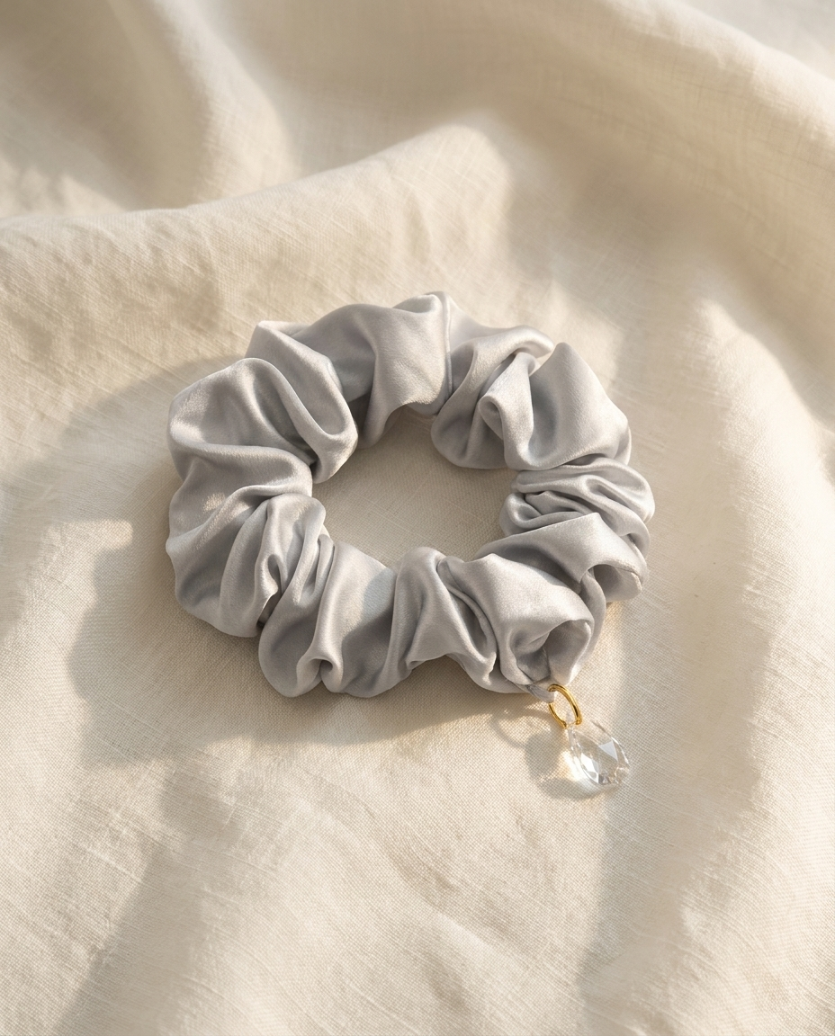 Chouchou en soie de mûrier gris perle Sleeping Zen avec breloque de cristal, sur lin ivoire
