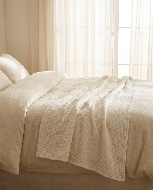 Couverture d'été en mousseline de coton ivoire Sleeping Zen drapée sur un lit