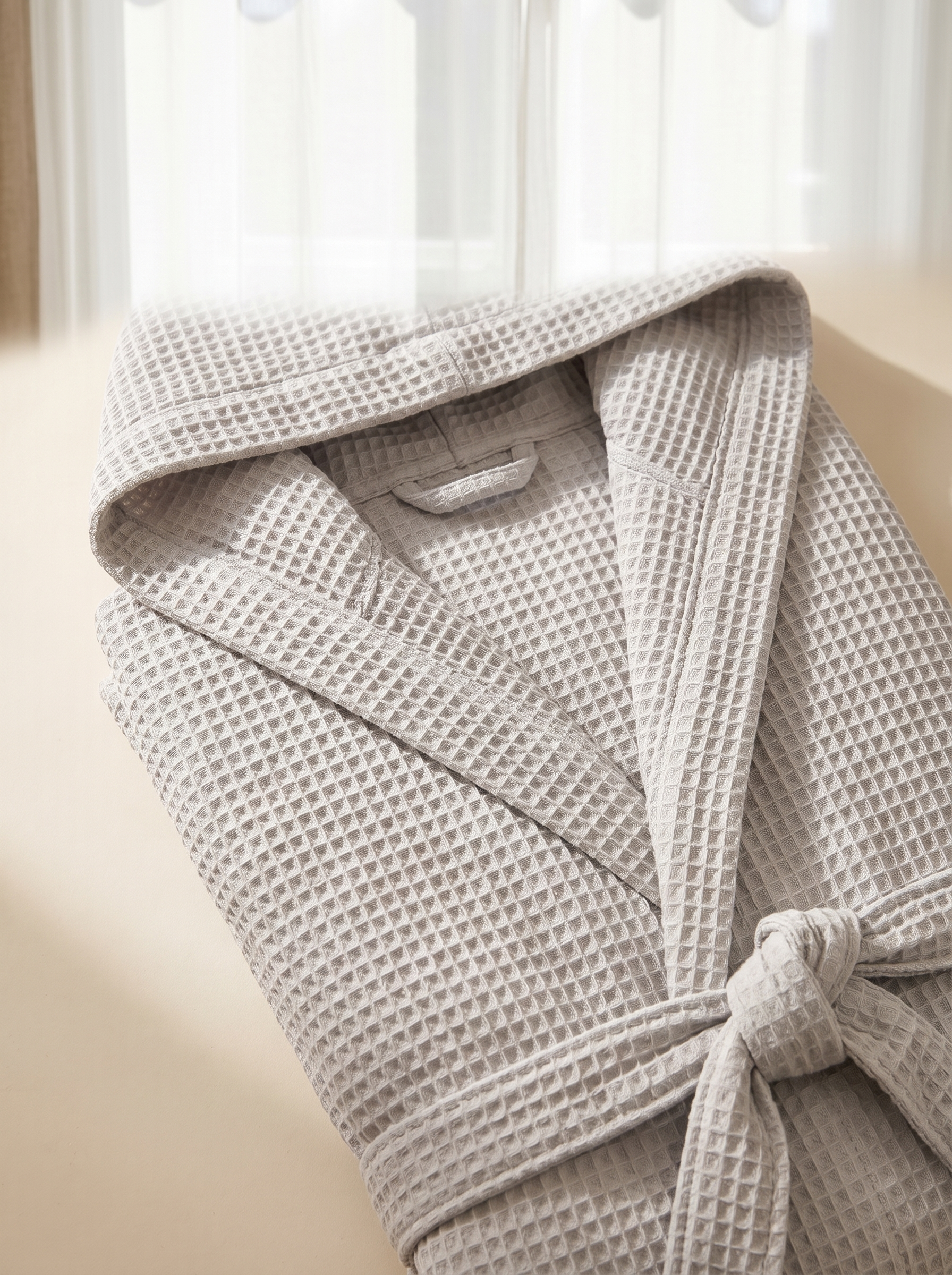 Détail de la capuche et de la ceinture du peignoir en coton gaufré gris clair, texture nid d'abeille